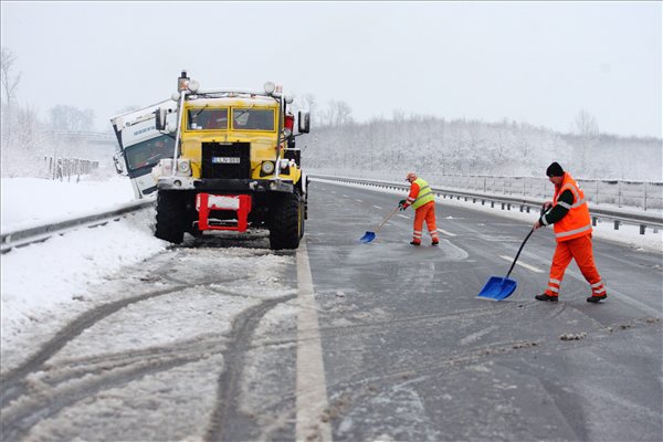 Takarítják az utat a közútkezelő munkatársai az M7-es autópálya 185-ös kilométerénél, ahol egy szlovák kamion megcsúszott és a szalagkorlátnak ütközött 2013. január 16-án. A műszaki mentés idejére a pálya Nagykanizsa felé vezető oldalát lezárták.MTI Fotó: Varga György