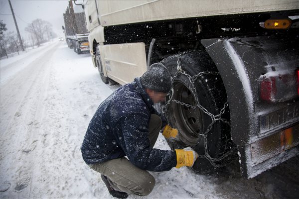 Hóláncot szerel egy sofőr a sűrű hóesésben elakadt kamionra a 61-es út bagolai emelkedőjénél Nagykanizsa közelében 2015. február 6-án. MTI Fotó: Varga György