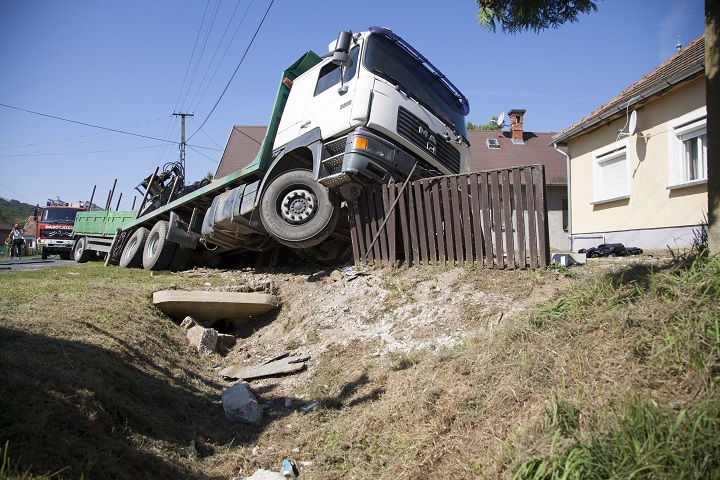 Összetört pótkocsis teherautó egy családi ház udvarán a Zala megyei Pákán 2016. augusztus 31-én. A fát szállító kamion átszakította a családi ház kerítését, és annak udvarán állt meg. A sofőr meghalt. MTI Fotó: Varga György