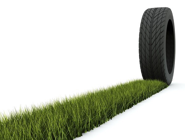 Tire with track from grass isolated on white